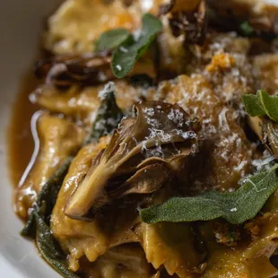 a bowl of pasta with mushrooms and sage leaves