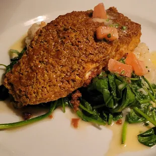 Pistachio-encrusted Pacific salmon atop risotto and garlic-sautéed spinach, finished with tomato-chive beurre blanc.