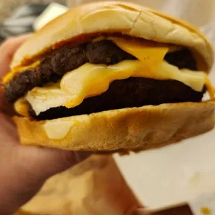 a hand holding a cheeseburger