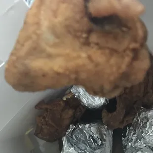 a hand holding a piece of fried chicken