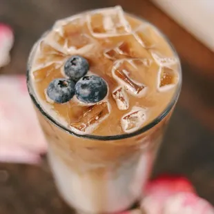 a glass of iced coffee with strawberries and blueberries