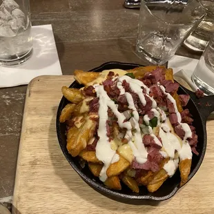 a skillet of french fries with bacon and gravy