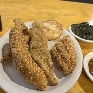 a plate of fried chicken with a side of greens