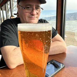 ows a man sitting at a table with a glass of beer