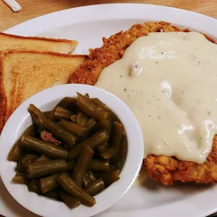 a plate of fried chicken with gravy and green beans