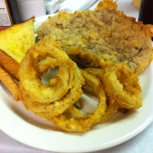 Chicken fried steak and onion rings with gravy on side