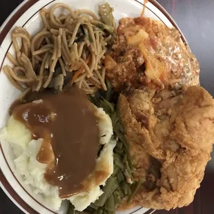 a plate of fried chicken, mashed potatoes, gravy and green beans