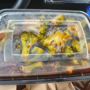a person holding a container of broccoli