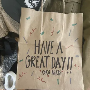 a person holding a paper bag that says have a great day