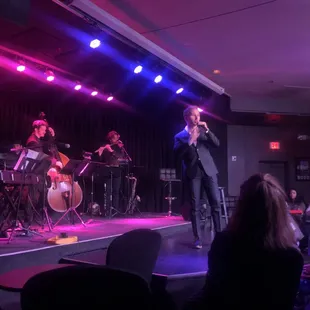  a man in a suit singing on stage
