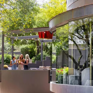 Three women enjoying cocktails on jade bar outdoor patio.