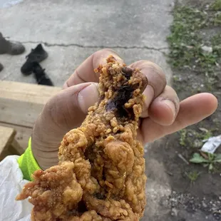 a hand holding a piece of fried chicken