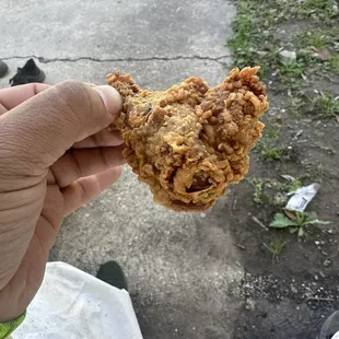 a hand holding a fried chicken
