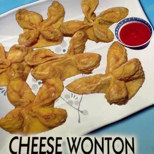 a plate of cheese wontons and dipping sauce
