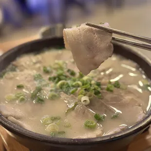 a bowl of soup with meat and green onions