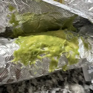 a burrito covered in guacamole