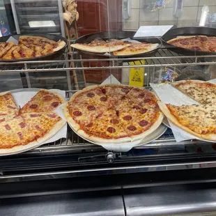 a variety of pizzas in a display case
