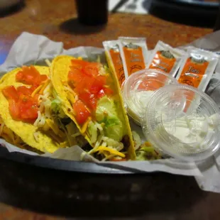 Crunchy ground beef tacos with hot sauces and sour cream on the side