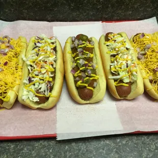four hot dogs with toppings