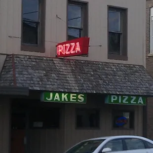 a car parked in front of a pizza shop