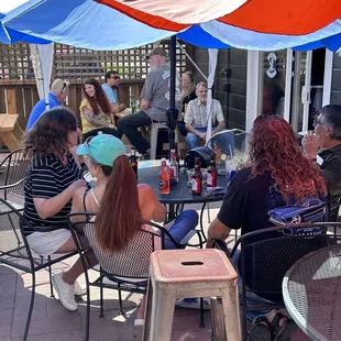 a group of people sitting at tables under umbrellas
