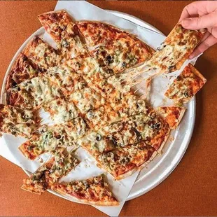 a hand grabbing a slice of pizza