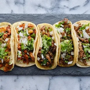 four tacos on a slate board