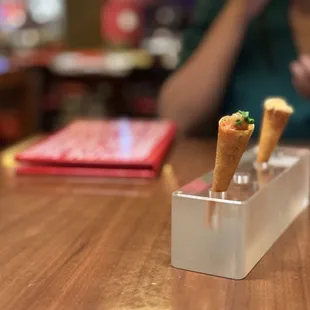 Cono de Mero Crudo y Escalivada in front, Cono de Queso de Cabra con Membrillo y Nueces in back