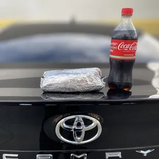 A picture of the burrito and a Coca-Cola sitting on the trunk of the car to give you an idea of the size.