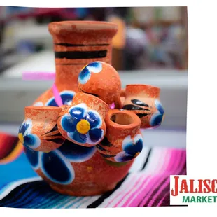 a clay vase with a flower decoration