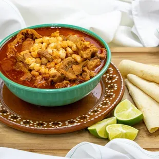 a bowl of jalapeno soup with tortillas and lime wedges