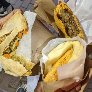 a person holding two sandwiches