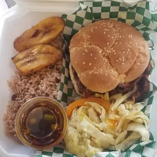 a hamburger, rice, and pickles in a styrofoam container