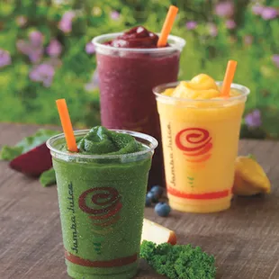 three smoothie cups with fruit and veggies