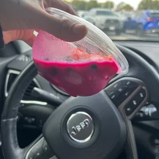 a hand holding a plastic container filled with pink liquid
