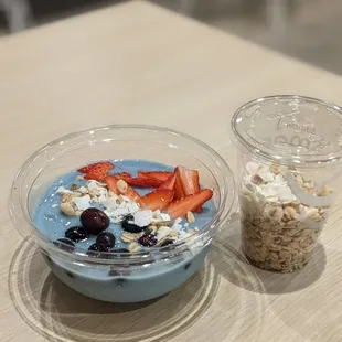 a bowl of oatmeal, strawberries, and a cup of yogurt