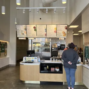 a woman standing at the counter of a fast food restaurant