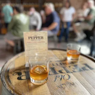 two glasses of whiskey on a barrel
