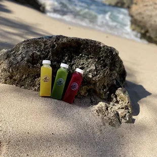 three bottles of juice on a beach