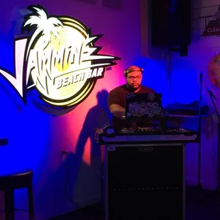 a dj in front of a neon sign