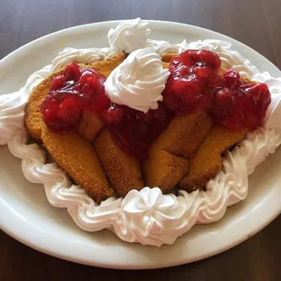 a plate of french toast with whipped cream and cherries
