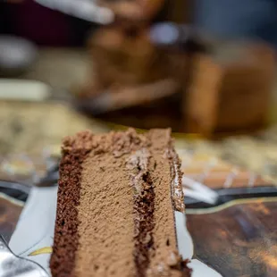 Chocolate Decadent Cake ($54) thin layers of chocolate cake and raspberry jam topped with chocolate ganache, shavings and mirror glaze