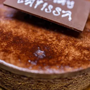 Chocolate Decadent Cake ($54) thin layers of chocolate cake and raspberry jam topped with chocolate ganache, shavings and mirror glaze