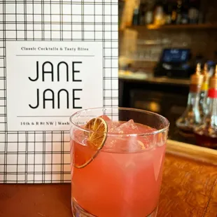 a pink cocktail with a slice of orange