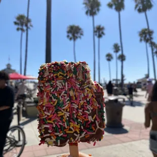 a hand holding a piece of food with sprinkles