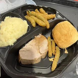 a tray of food including a sandwich, mashed potatoes, and a roll