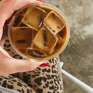 a woman holding a glass of iced coffee