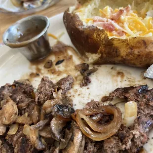 Hamburger steak with grilled onions and mushrooms and baked potato.