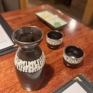 a table with a vase and cups on it