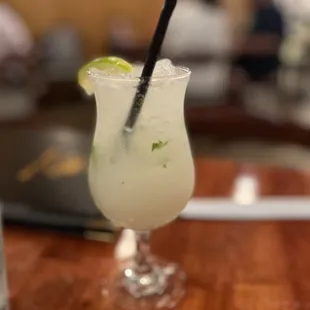 a drink with a straw and lime garnish